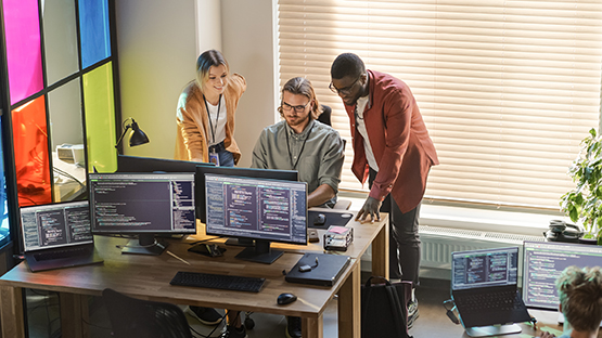 Three people gathered at a desk working together
